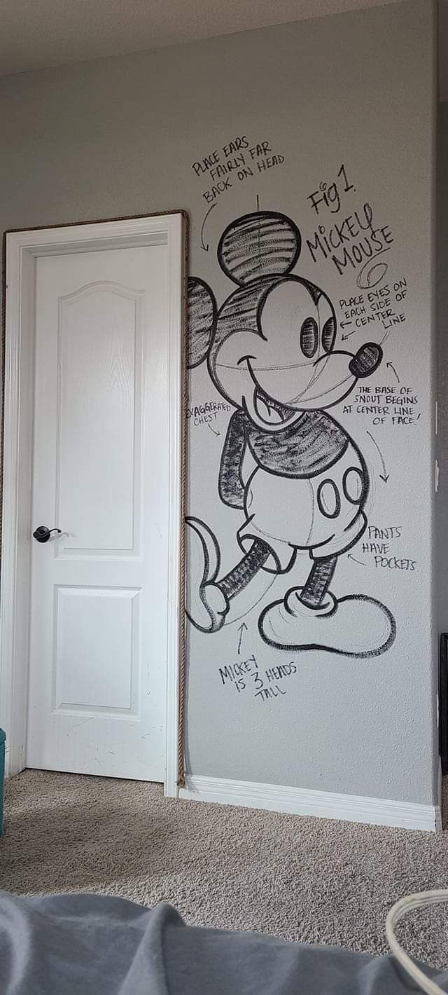 a bedroom with a mickey mouse mural on the wall next to a bed and door