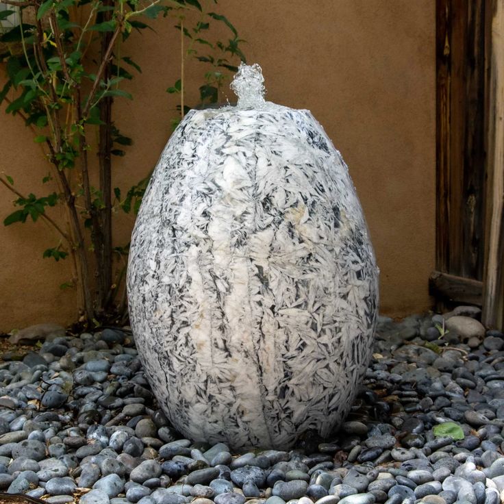 a large white vase sitting on top of a pile of rocks