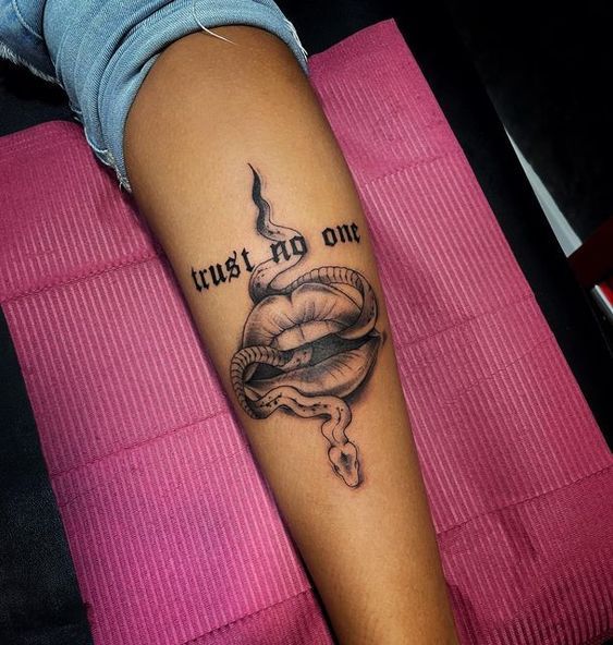 a woman's arm with a tattoo that says trust my one on it and a snake