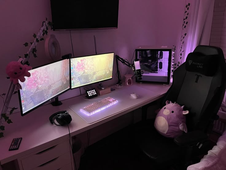 a computer desk with two monitors and a stuffed animal