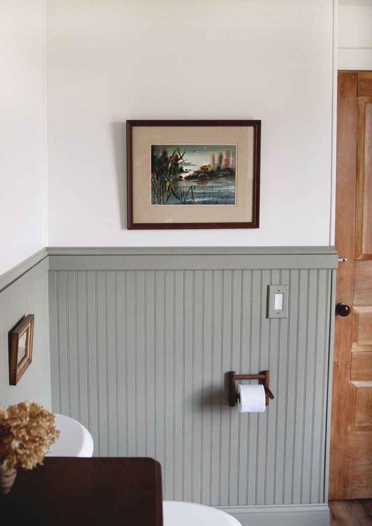 a bathroom with a painting on the wall and toilet paper dispenser