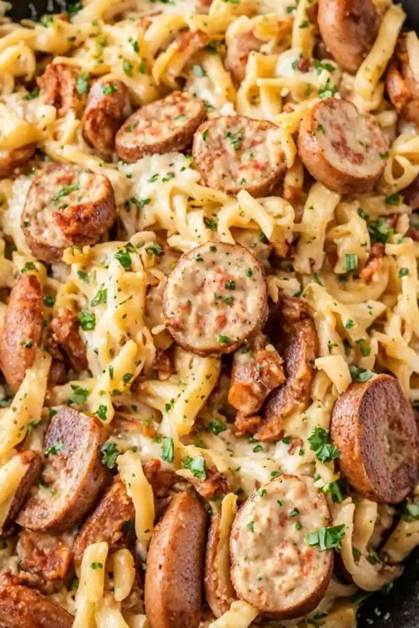 sausage and pasta in a skillet with parmesan cheese on the side, ready to be eaten