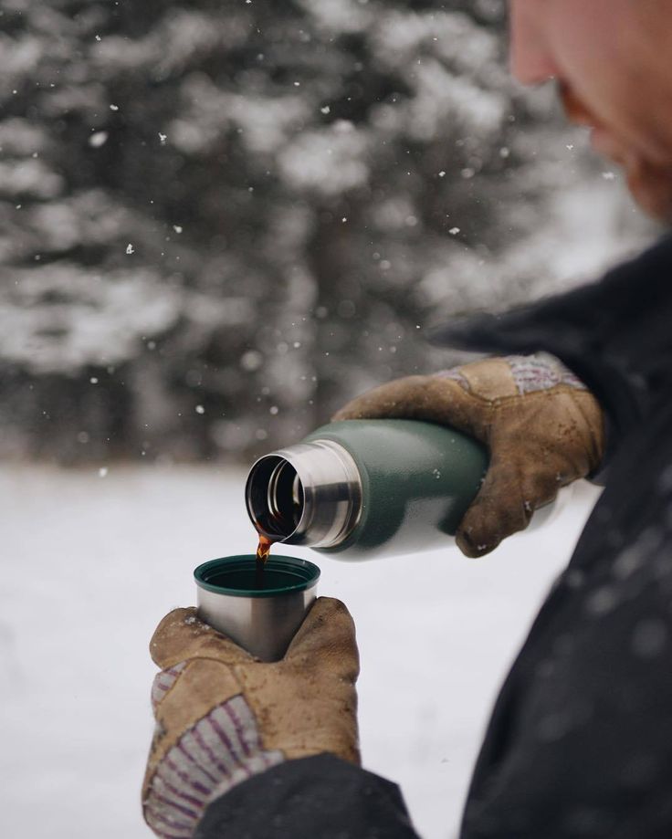 a person pouring something into a cup in the snow