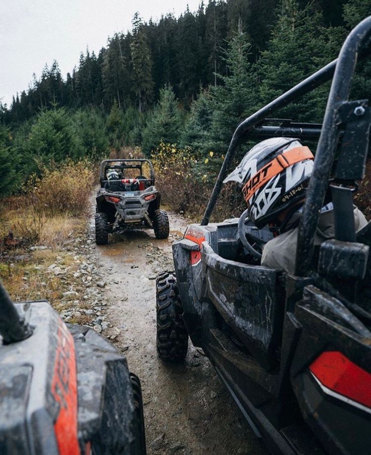 two atvs driving down a trail in the woods