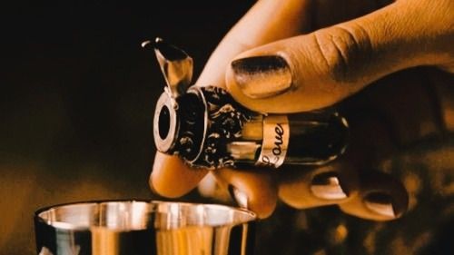 a person is pouring some wine into a small glass with a silver cup in the foreground