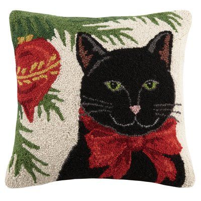 a black cat with a red bow on it's neck is sitting in front of a christmas tree