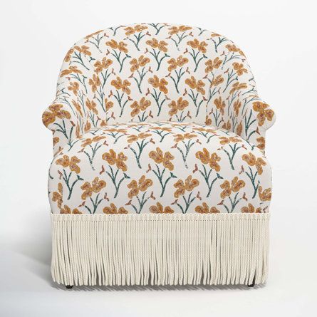 an upholstered chair with fringes and flowers on the back, against a white background