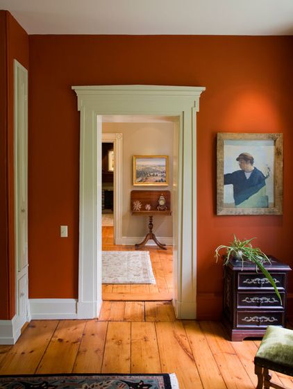 an orange room with wooden floors and white trim on the walls is pictured in this image