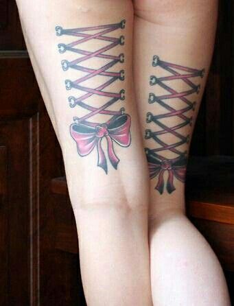 two women with tattoos on their legs are tied up to each other and one has a pink bow