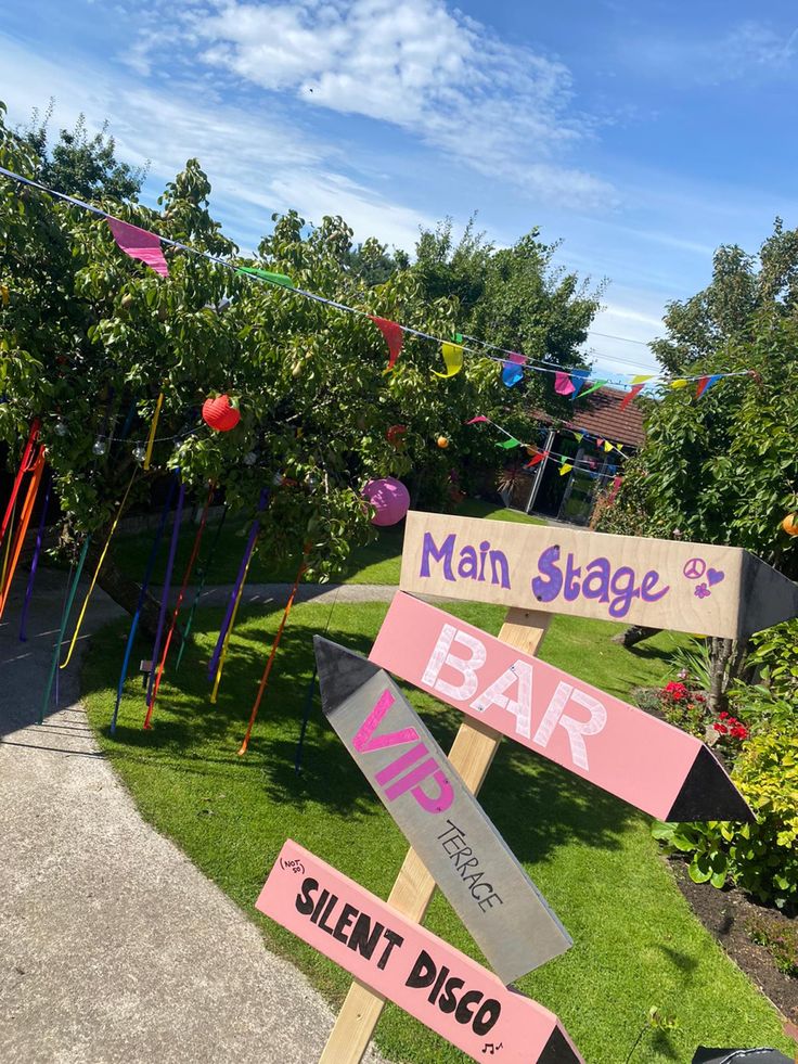 a wooden sign with many different signs on it's sides in front of some trees