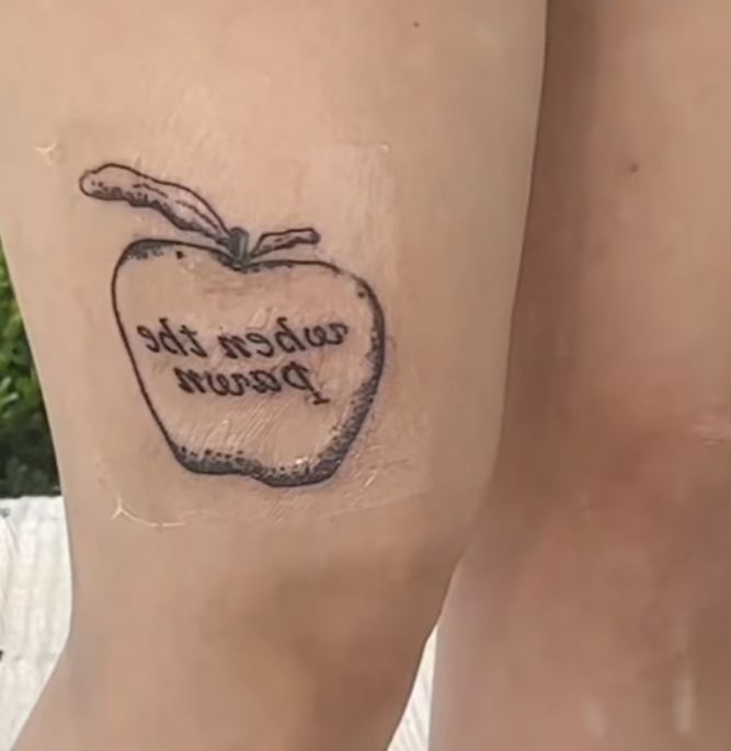 a woman's leg with an apple tattoo that reads, when the prawn