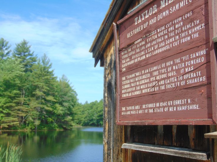 a sign on the side of a wooden building next to a body of water with trees in the background