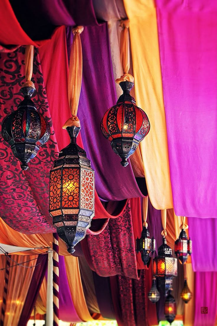 several colorful lanterns hanging from the ceiling in a room filled with drapes and curtains