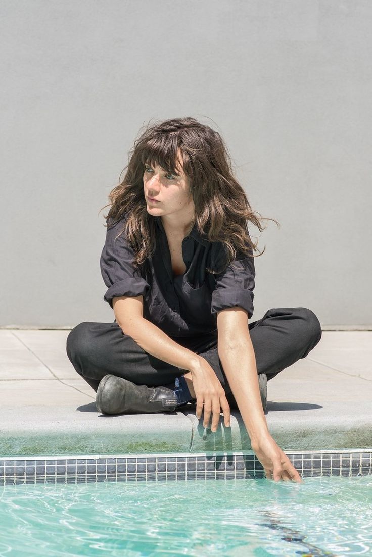 a woman sitting on the edge of a swimming pool