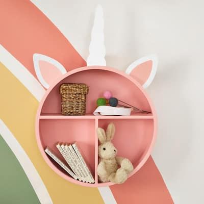 a pink shelf with some books and stuffed animals on it in front of a rainbow painted wall