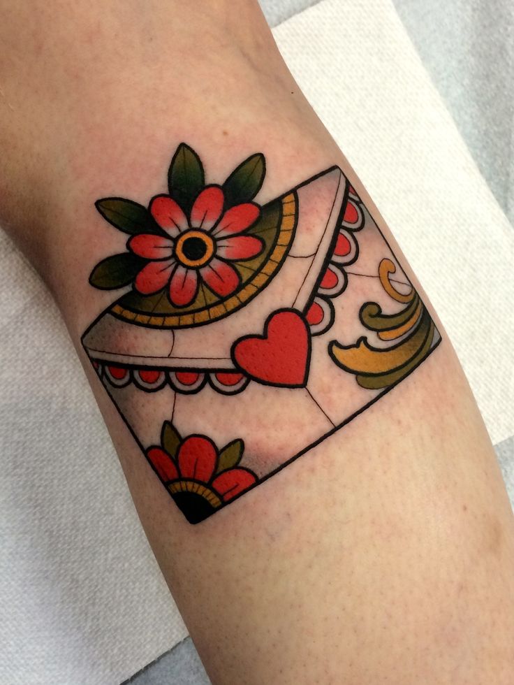 a woman's arm with a heart and flower tattoo design on the left forearm