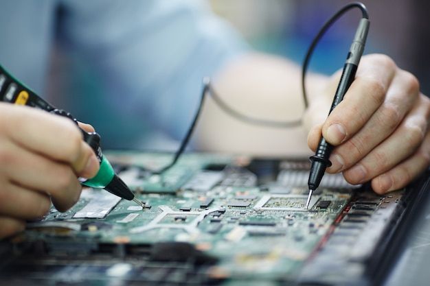 two hands are working on an electronic circuit board