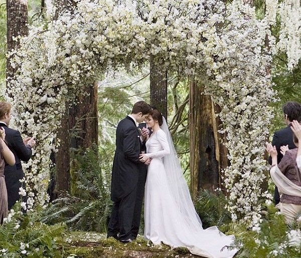 a bride and groom standing under an arch covered in white flowers