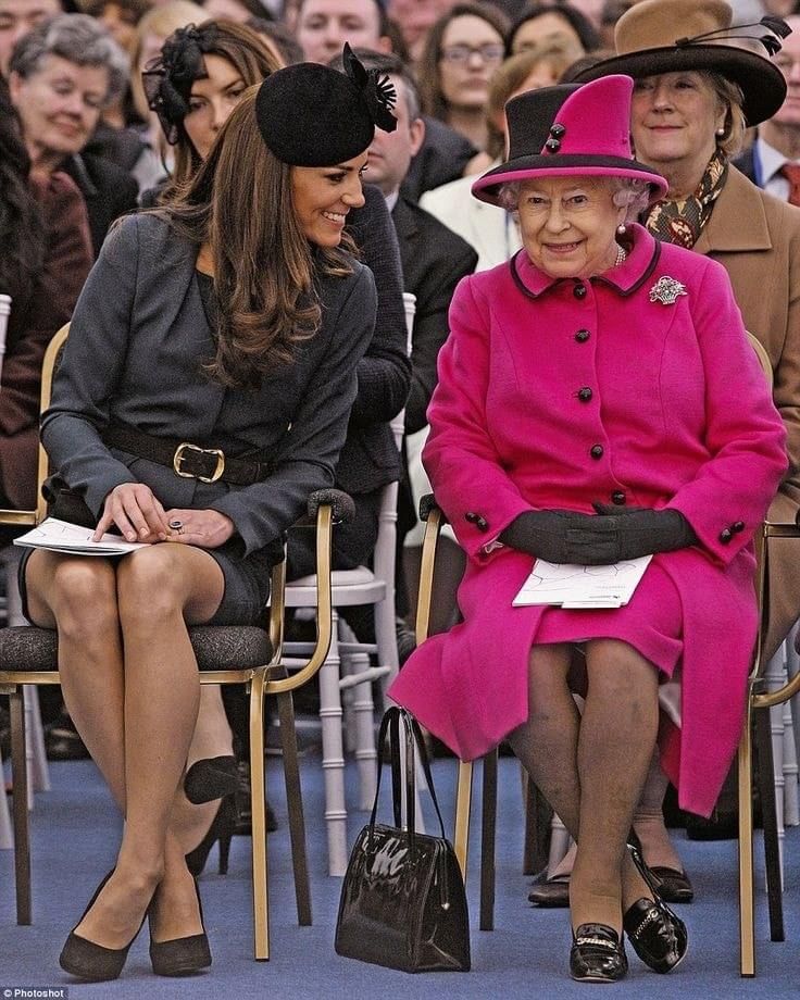 two women sitting next to each other on chairs in front of a large group of people