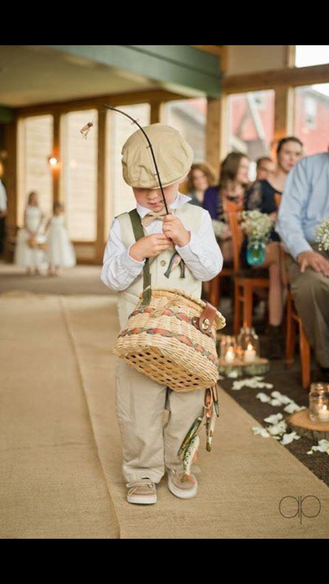 a little boy standing in front of a crowd holding a basket and fishing rod while wearing a hat