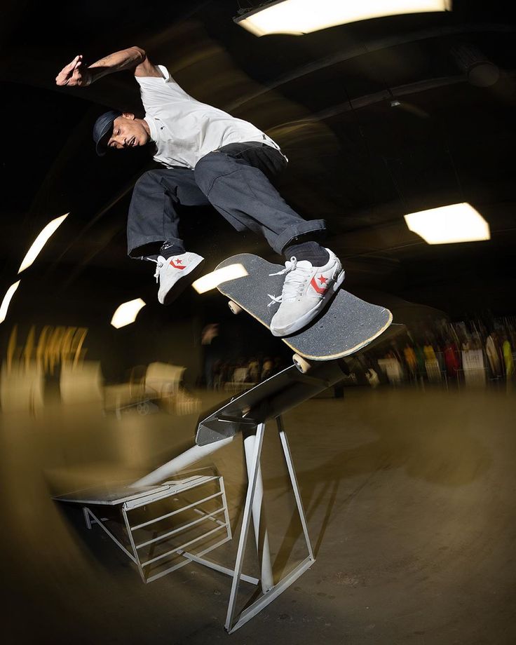 a man riding a skateboard up the side of a metal rail in a dark room