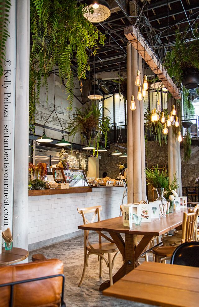 the inside of a restaurant with tables, chairs and potted plants hanging from the ceiling