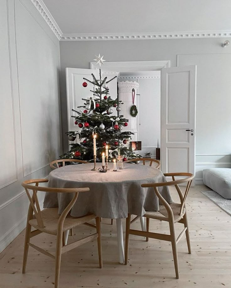 a small christmas tree sits in the corner of a room with two chairs and a table