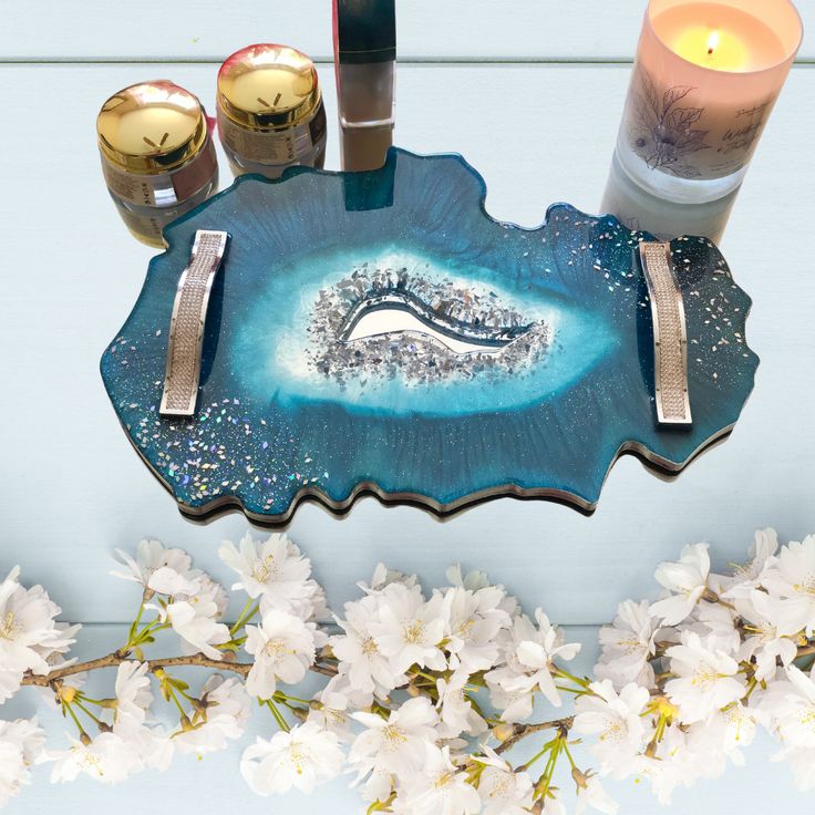 a blue tray with candles and other items on it next to some white flowered branches