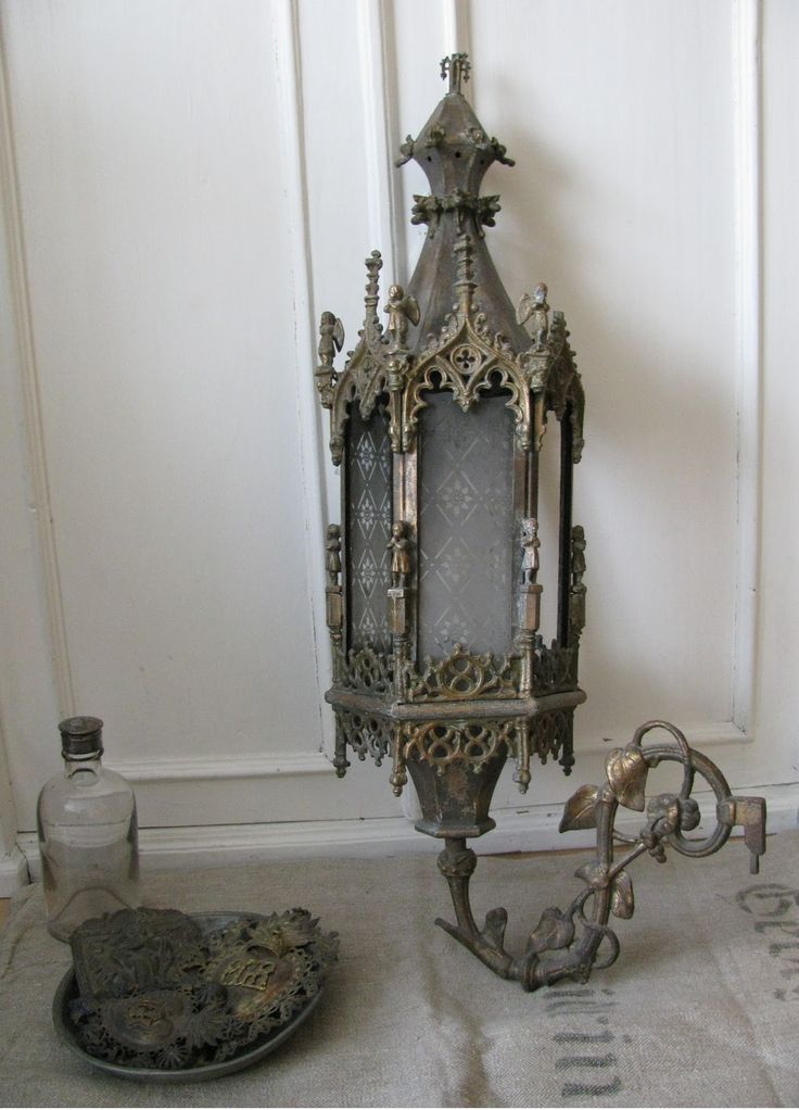 an ornate metal lantern sitting on top of a table next to a glass bottle and tray