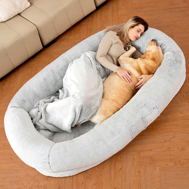 a woman laying on top of a dog bed