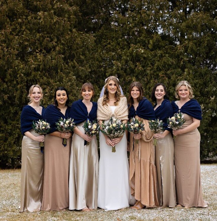 a group of women standing next to each other wearing dresses and holding bouquets in their hands