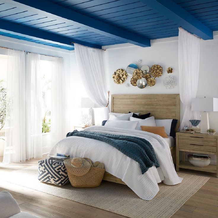 a bedroom with blue painted ceiling and white bedding in the center, along with wooden flooring