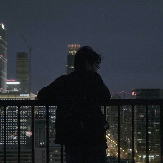 a man standing on top of a balcony next to a tall building in the city