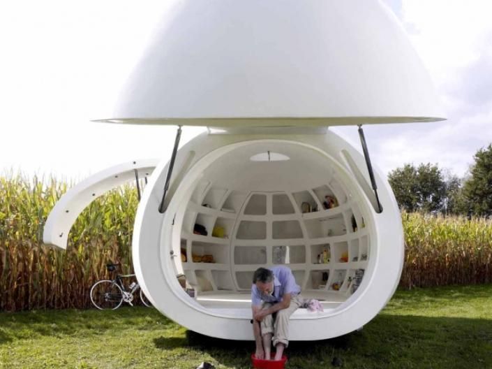 a man sitting on top of a large white object in the middle of a field