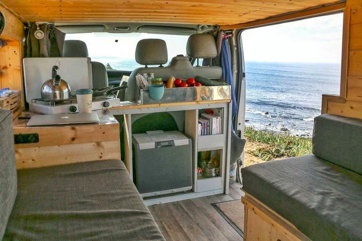 the interior of a camper van with an open kitchen and living area next to the ocean