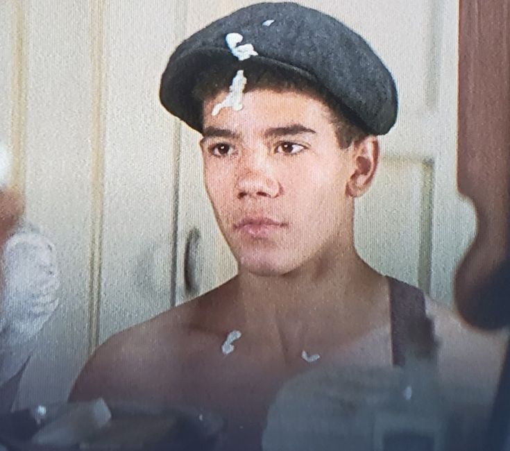 a young man wearing a hat and looking in the mirror