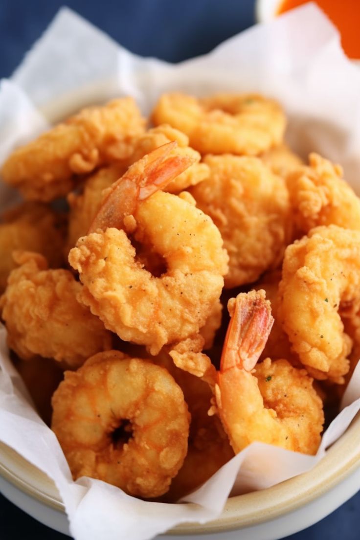 a bowl filled with fried shrimp sitting on top of a table