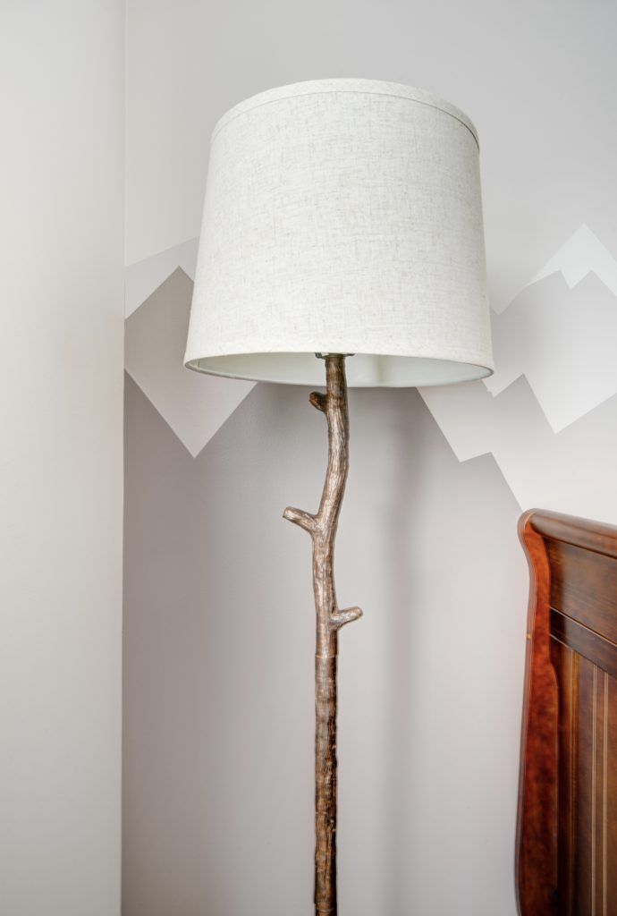 a lamp that is on top of a wooden table next to a dresser and bed