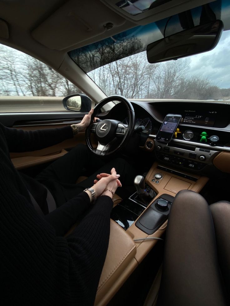 a woman sitting in the driver's seat of a car with her hands on the steering wheel