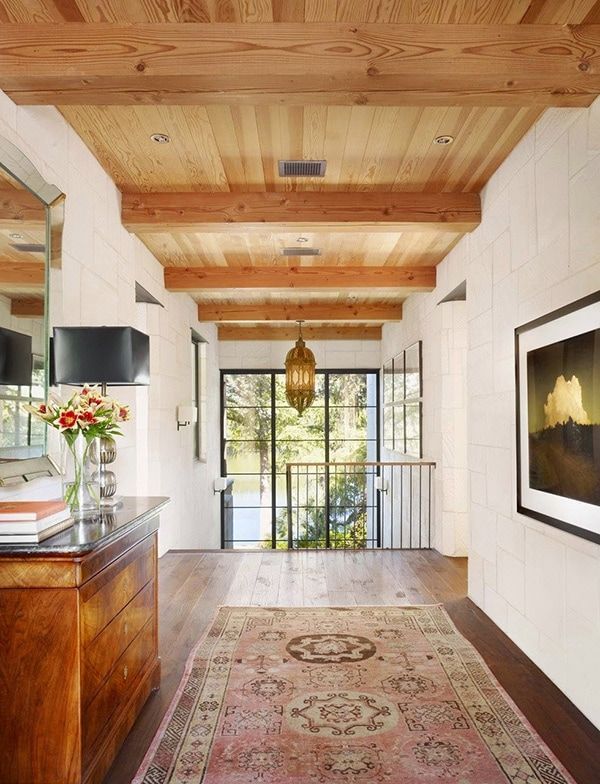 a hallway with wooden floors and white walls has a large rug on the floor next to it