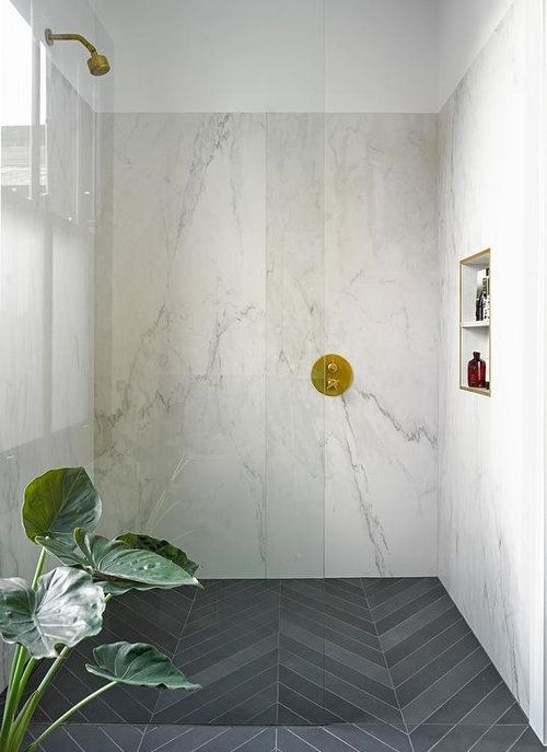 a bathroom with white walls and marble flooring, along with a plant in the corner