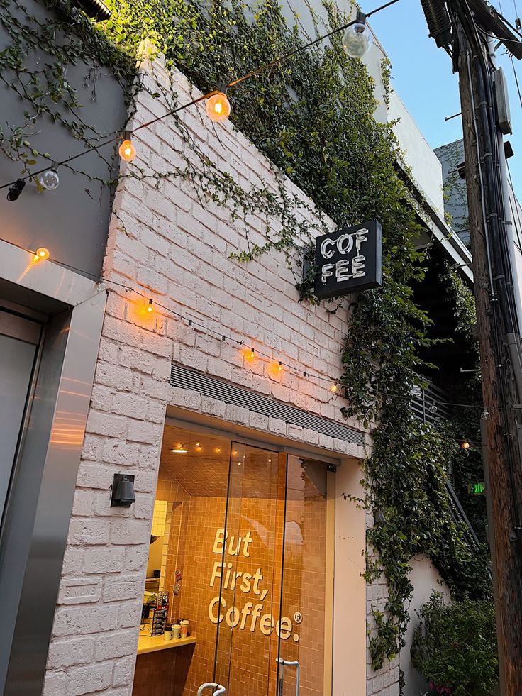 the outside of a coffee shop with vines growing on the building's wall and windows