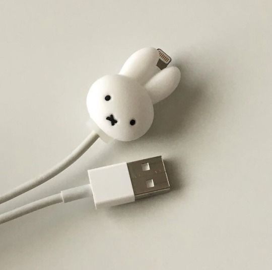 an earphone plugged in to a charger on top of a white surface