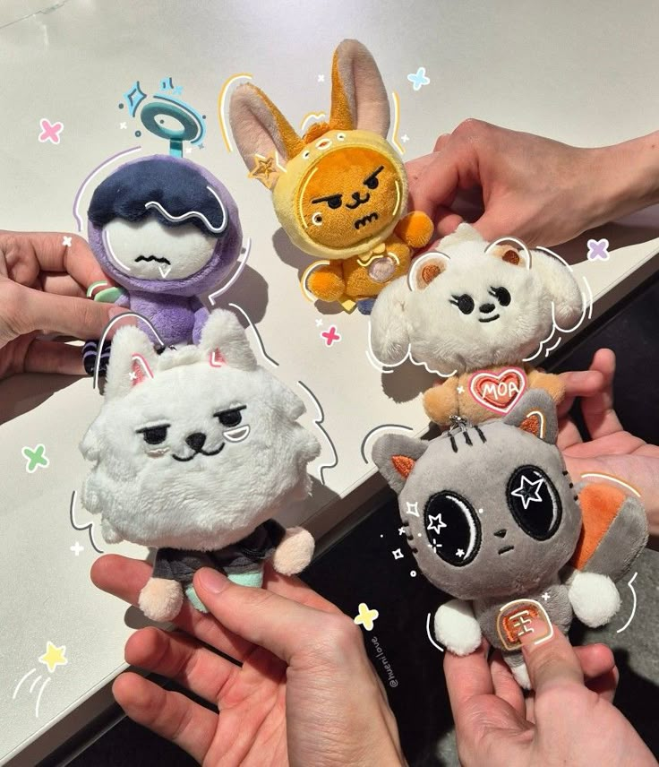 several small stuffed animals are being held by someone's hands in front of them