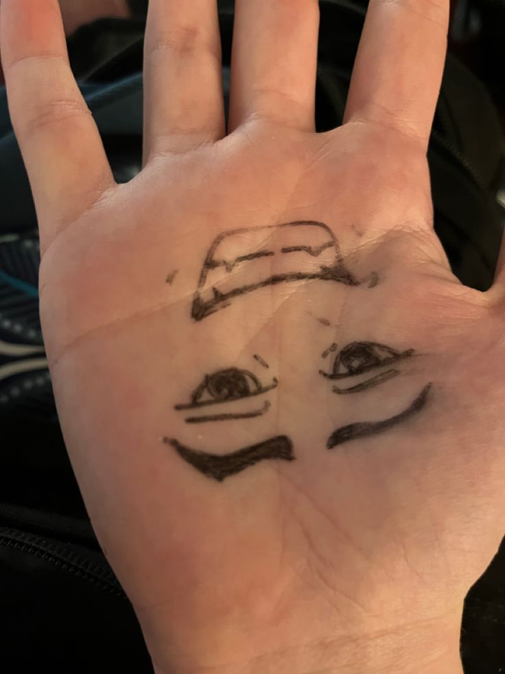 a person's hand with a face drawn on it and two eyes drawn on the palm