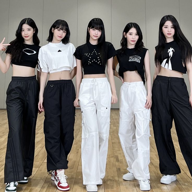 four girls in black and white outfits standing on a wooden floor