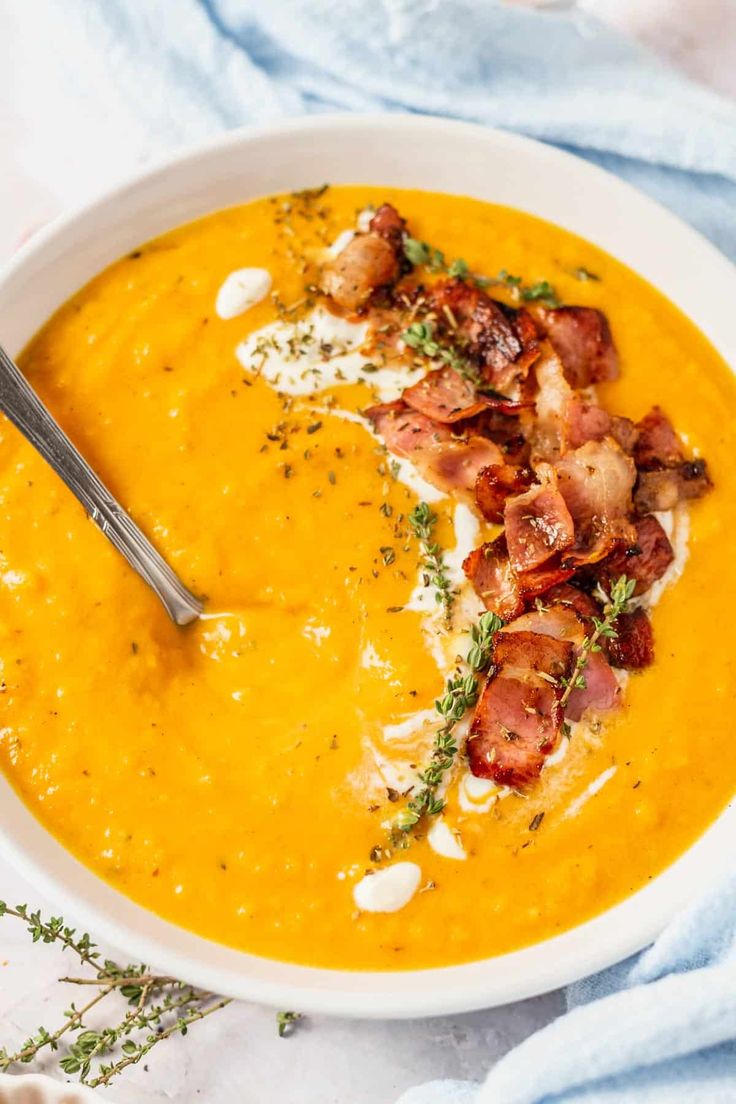 a bowl of butternut squash and sweet potato soup with coconut milk on the side