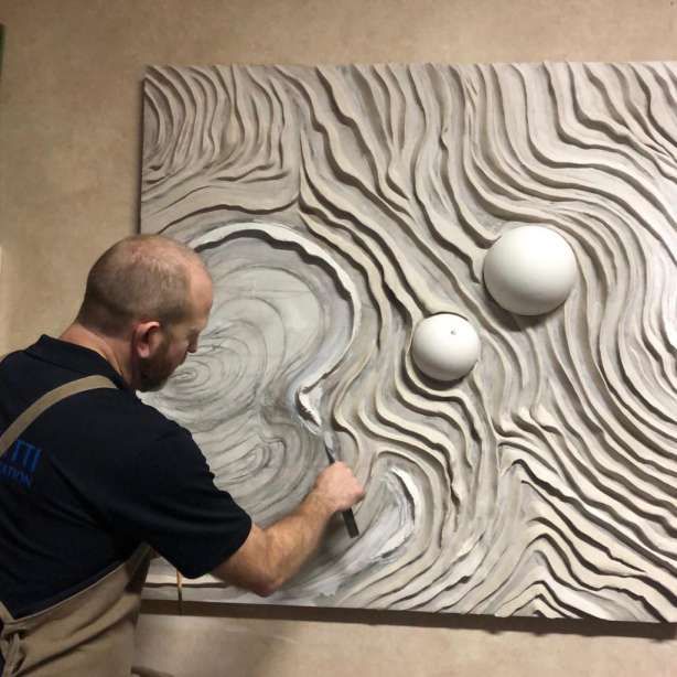 a man is working on an art work in the process of being made with marble