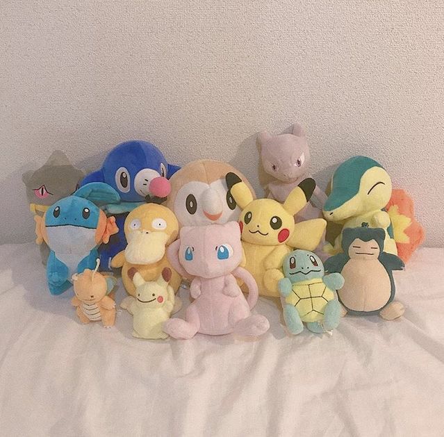 a group of pokemon stuffed animals sitting on top of a white bed cover covered in sheets