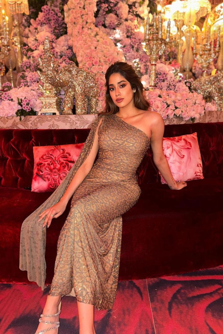 a woman sitting on top of a red couch in front of a floral wall with pink flowers